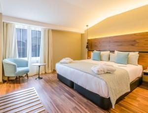 a hotel room with a large bed and a blue chair at Vincci Liberdade in Lisbon