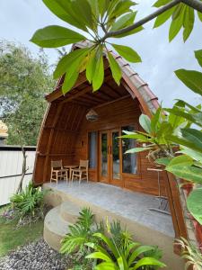 a wooden house with a round roof with a patio at WArDiTa Paddy Lodge in Labuhanamuk +6 photos