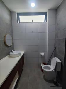 a bathroom with a toilet and a sink and a window at Kuching Podium Apartment Near Aeon Mall 3rd Mile in Kuching