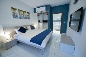 a white and blue bedroom with a bed and a mirror at The Exiles Hotel in Sliema