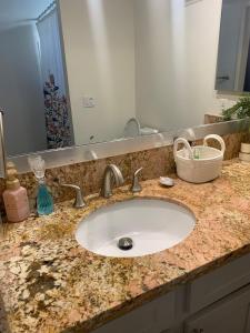 a bathroom counter with a sink and a mirror at Sunny Retro Row Condo- Walk to Beach! in Long Beach