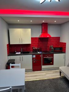 a kitchen with white cabinets and a red wall at Blackpool Beach Holiday Flats in Blackpool +39 photos
