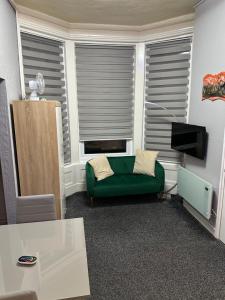 a living room with a green couch in front of a window at Blackpool Beach Holiday Flats in Blackpool