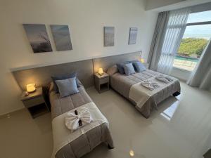 a hotel room with two beds and a window at Nacar Apart Hotel in Santa Teresita