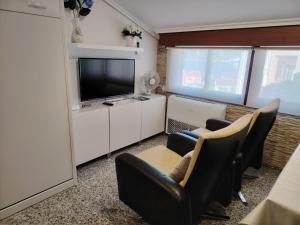 a living room with a flat screen tv and chairs at Ático tipo Loft centro de Mugardos in Mugardos