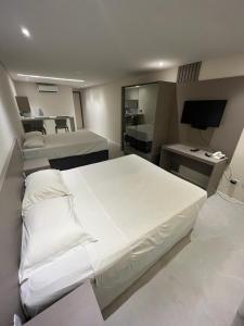 ein Schlafzimmer mit einem großen weißen Bett und einem Schreibtisch in der Unterkunft Flat Frente Mar em Cabo branco - Ambassador in João Pessoa + 9 Fotos