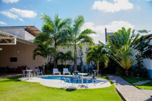 une cour avec une piscine, des chaises, des tables et des palmiers dans l'établissement Hotel Oceania, à Eunápolis