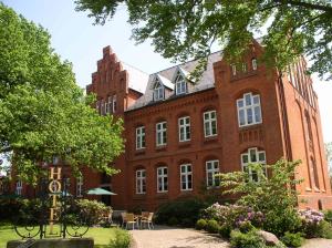 un gran edificio de ladrillo rojo con mesas y sillas en Hotel Altes Gymnasium, en Husum