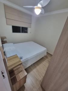 a small bedroom with a white bed and a table at Apartamento Reformado - Pampulha in Belo Horizonte