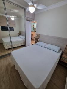 a large white bed in a room with a mirror at Apartamento Reformado - Pampulha in Belo Horizonte