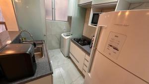 a small kitchen with a refrigerator and a sink at Apartamento Reformado - Pampulha in Belo Horizonte +5 photos