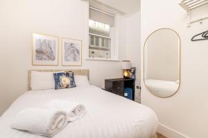 een witte slaapkamer met een wit bed en een spiegel bij Penthouse Collection by EPIC in Liverpool