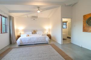 a bedroom with a white bed and a bathroom at Aardvark Bioreserve in Ladismith