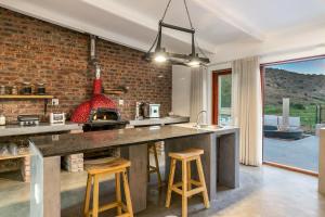 a kitchen with a brick wall and a kitchen island with stools at Aardvark Bioreserve in Ladismith