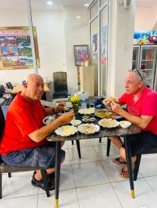 dos hombres sentados en una mesa comiendo comida en Walking Street Pattaya Beach Ordinary Rooms Guest House วอล์คกิ้งสตรีทพัทยาชายหาดพัทยาห้องธรรมดาเกสท์เฮ้าส์, en Pattaya central