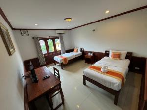 a bedroom with two beds and a desk and a table at Savan Villa Hotel in Savannakhet