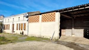 an old white building with a large garage at Joli gîte dans une installation équestre in Donnezac
