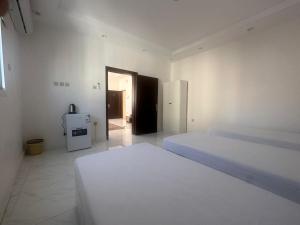 a white room with two beds and a refrigerator at دانة - Dana in Medina +9 photos