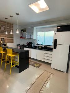 eine Küche mit gelben Stühlen und einer schwarzen Arbeitsplatte in der Unterkunft Praia do Flamengo 150m da praia Casa Ballalai in Salvador