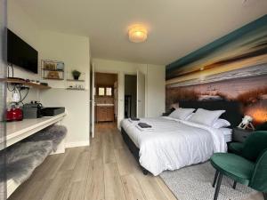 a bedroom with a large bed and a green chair at Buiten Gewoon in De Koog