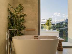 Una bañera en un baño con una ventana grande. en Villa 11 Sunset, en Marbella 21 fotos más
