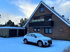 a car parked in front of a house in the snow at Küsten Koje in Sankt Peter-Ording