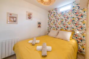 Un dormitorio con una cama amarilla con toallas. en Sollys (Hyper centre - Parking - Cosy), en Auxerre