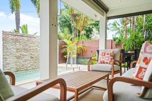 un portico con due sedie e un tavolo in legno di Sunhaven Palm Cove 3 Bedroom House with Pool, AC & Free Parking a Palm Cove