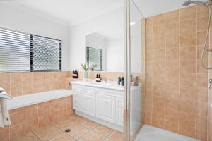 a bathroom with a tub and a sink and a shower at Palm Cove House in Trivia in Palm Cove