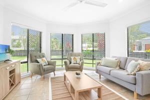 a living room with couches and chairs and windows at Palm Cove House in Trivia in Palm Cove