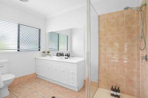 a bathroom with a white sink and a shower at Palm Cove House in Trivia in Palm Cove