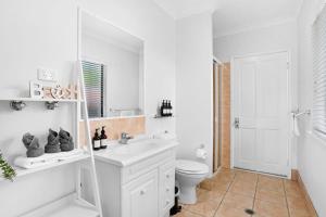 a white bathroom with a toilet and a sink at Palm Cove House in Trivia in Palm Cove