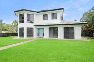 a white house with a green lawn at Palm Cove House in Trivia in Palm Cove