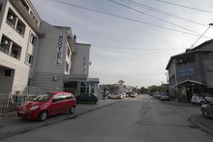 een kleine rode auto geparkeerd aan de kant van een straat bij Hotel Golf in Kruševac