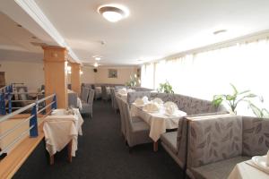 uma sala de jantar com mesas e cadeiras com roupa de mesa branca em Hotel Golf em Kruševac
