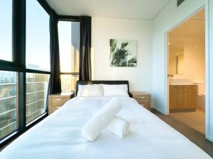 ein Schlafzimmer mit einem großen weißen Bett mit zwei Kissen in der Unterkunft High-Rise Heaven - West Franklin in Adelaide + 15 Fotos