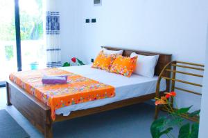 a bedroom with a bed with orange and white pillows at White rose villa in Weligama