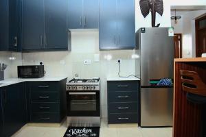 a kitchen with blue cabinets and a stainless steel refrigerator at The Hause in Nakuru +9 photos