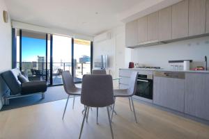 Rundle Retreat - 2BR Apartment with stunning views في أديلايد: مطبخ مع طاولة وكراسي في الغرفة