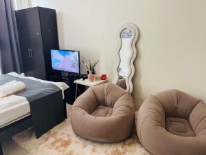 a bedroom with two chairs and a bed and a mirror at The Wild Roces Makati, The Beacon Residences in Manila