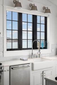 een witte keuken met een wastafel en 2 ramen bij Water’s Edge Private Frontage + Dock Hot Tub AC in Traverse City