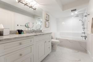 een witte badkamer met een bad, een toilet en een wastafel bij Water’s Edge Private Frontage + Dock Hot Tub AC in Traverse City +35 foto's