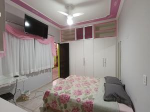 a bedroom with a bed and a tv on the wall at Pousada Hostel Raizer in Campo Grande