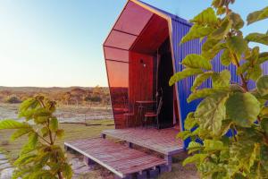 a blue and red house with a wooden porch and a chair at Chalé Henri Salvador na Vinícola Reconvexo in Morro do Chapéu