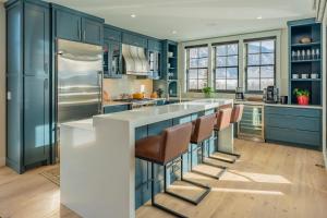 a kitchen with blue cabinets and a large island with bar stools at Academy Place | Glacier Lily Penthouse in Crested Butte