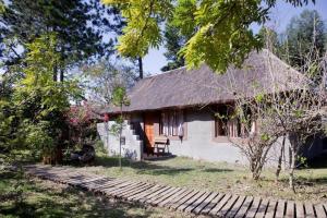 mały domek z dachem krytym strzechą i ścieżką w obiekcie Triton Dive Lodge (Pty) Ltd w mieście Sodwana Bay