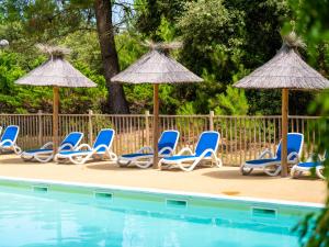 a group of chairs and umbrellas next to a pool at Domaine Résidentiel de Plein Air Monplaisir in Saint-Trojan-les-Bains