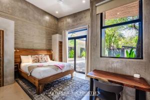 a bedroom with a bed and a desk and a window at Steps to the Main Surf Break - 3 Bedroom House in Refundores +30 photos