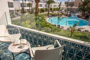a balcony with a table and chairs and a swimming pool at Oasis Lanz Beach Mate in Costa Teguise