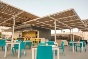 a cafeteria with tables and blue chairs in a building at Oasis Lanz Beach Mate in Costa Teguise